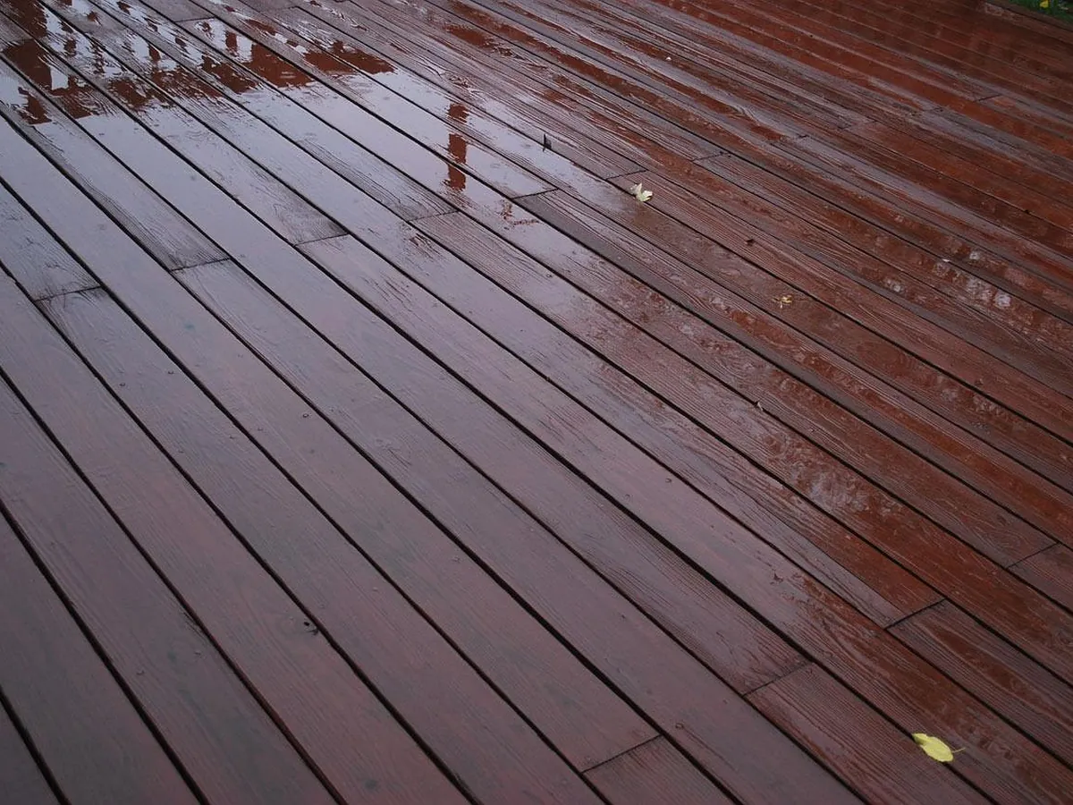 Rich brown timber deck boards running toward a garden, damp and freshly cleaned