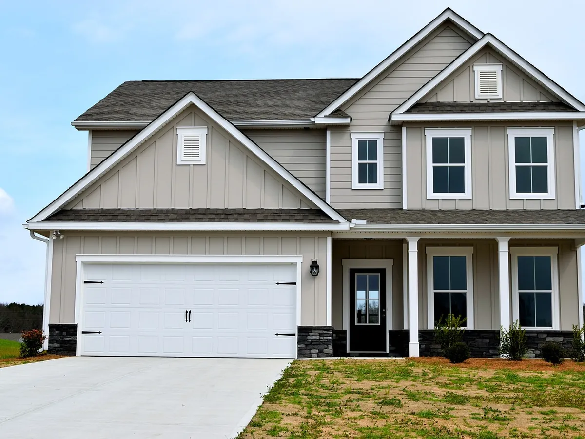 A pale grey two storey house with clean siding, white trim and a tidy front lawn